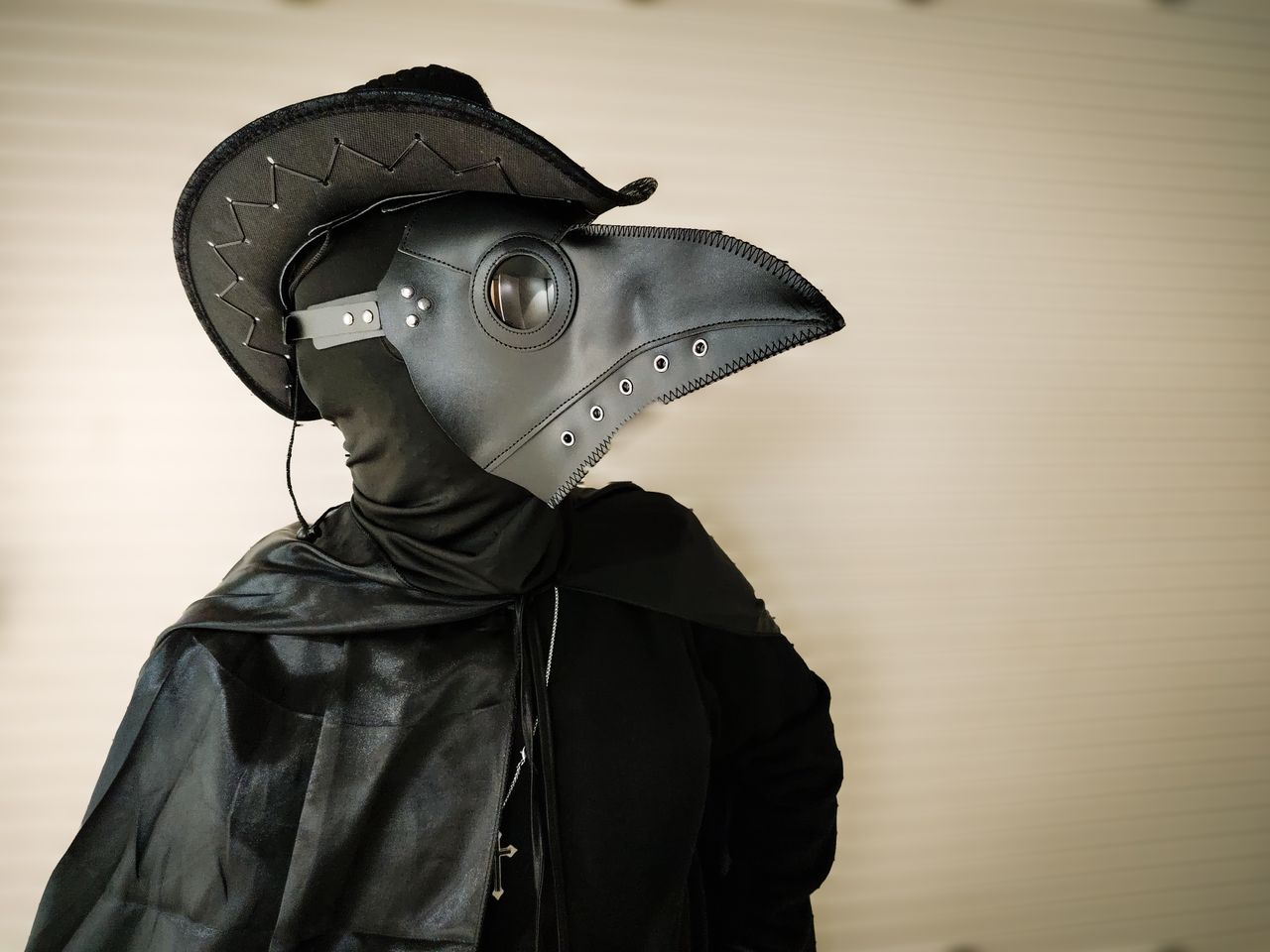 a person in a plague doctor outfit wearing a beaked mask and black clo