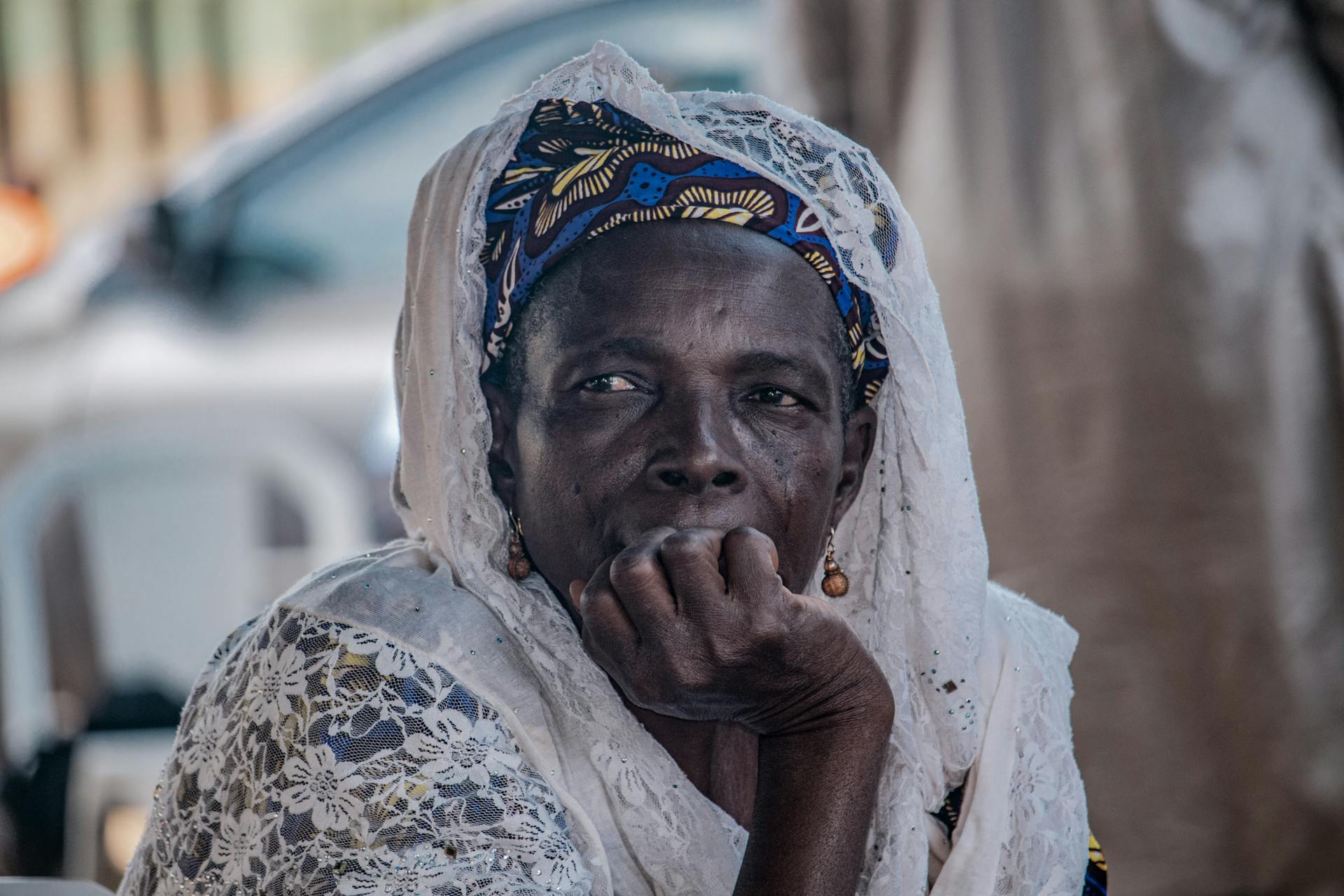 Close-up portrait of an elderly Nigerian woman in traditional attire, deep in thought.