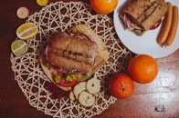 Top view of a gourmet sandwich with citrus fruits and sausages, perfect for an outdoor brunch.