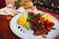 Savor a traditional Romanian meal featuring juicy beef, polenta, and fresh vegetables, perfect for a culinary adventure.