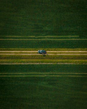 在荷兰文洛一条被广阔绿地包围的乡村道路上，无人机拍摄了一辆汽车