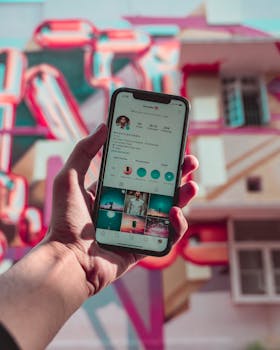 一只手握着显示社交媒体的智能手机，映衬着色彩缤纷的城市壁画