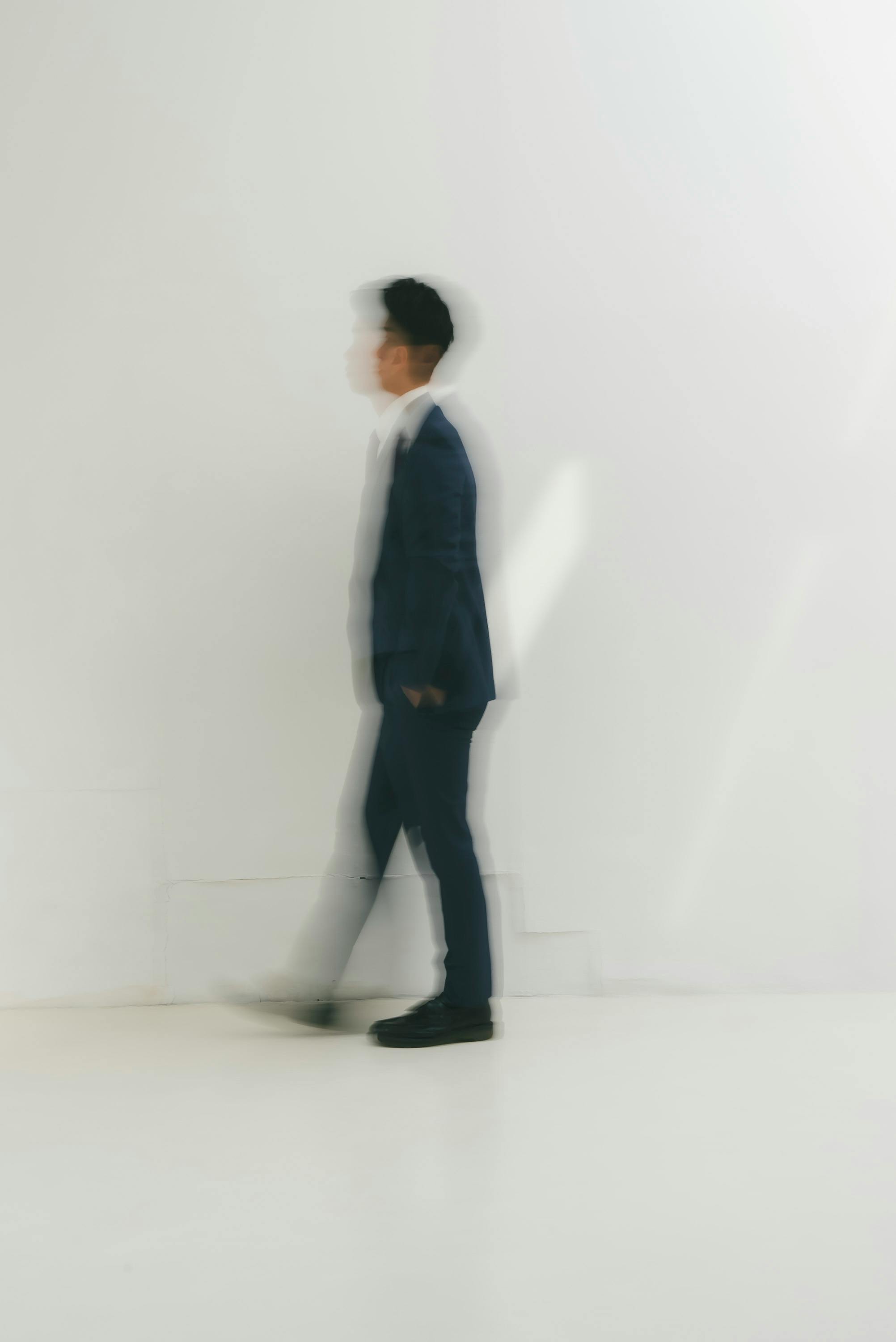 Blurry image of a person in a suit walking, creating an abstract effect.