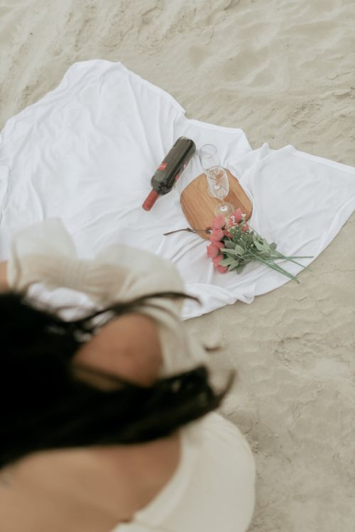 Free Intimate beach picnic setup featuring wine, flowers, and a relaxing atmosphere. Stock Photo