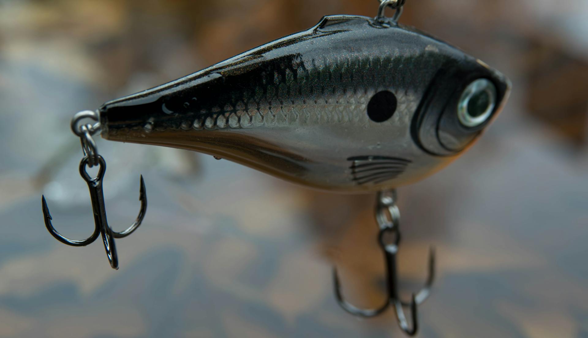 Detailed view of a shiny fish-shaped fishing lure above water surface.