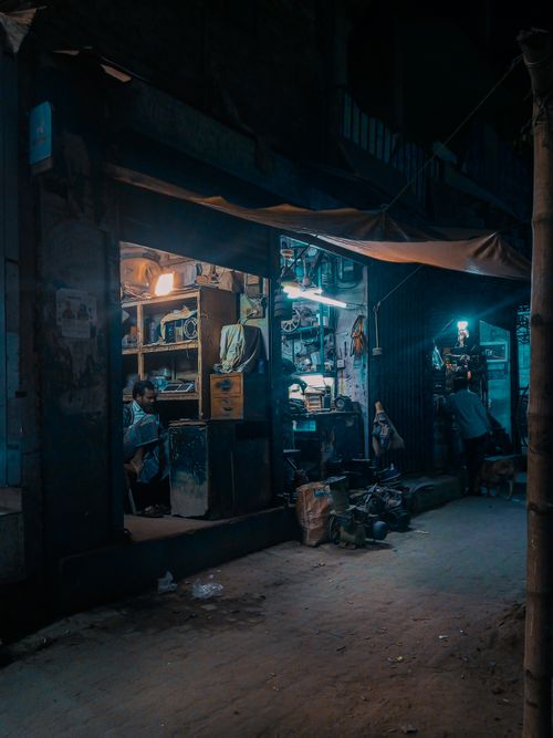 Free Cinematic view of a small shop in Dhaka at night with teal lighting and urban life ambiance. Stock Photo