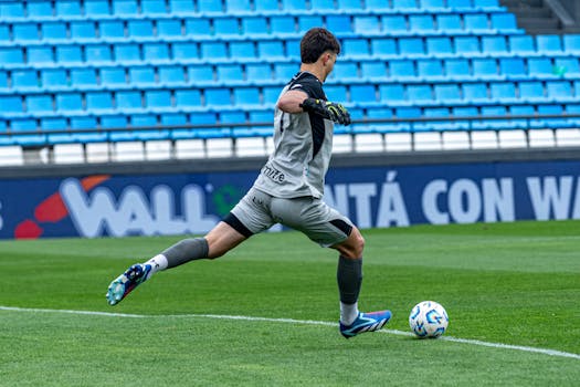 Soccer player kicking a ball in an empty stadium, showcasing athleticism and sportsmanship.