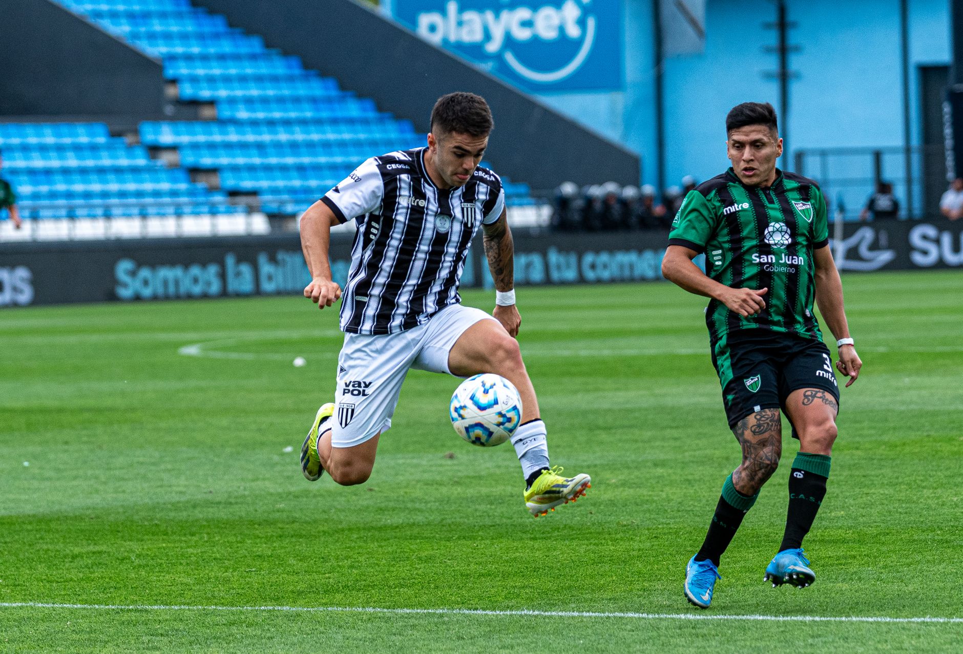 Two football players competing in a small-sided 3v3 game, one changing direction under intense defensive pressure