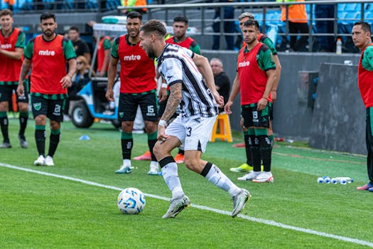 Soccer player in action on the field with team members watching.