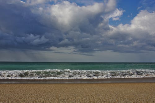 Waves Breaking on a Beach Under a Cloudy Sky 