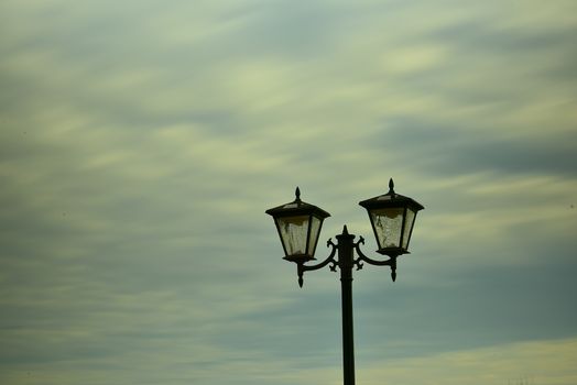 A striking silhouette of a vintage street lamp set against a soft, cloudy sky, offering a timeless aesthetic.