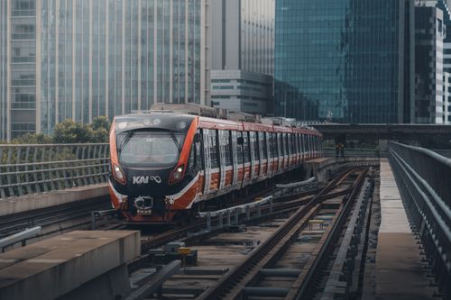 Free A modern train riding through urban tracks in Jakarta, showcasing the city's dynamic architecture. Stock Photo