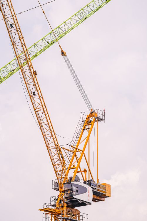 Free A towering yellow and green construction crane against a cloudy sky in Jakarta, Indonesia. Stock Photo