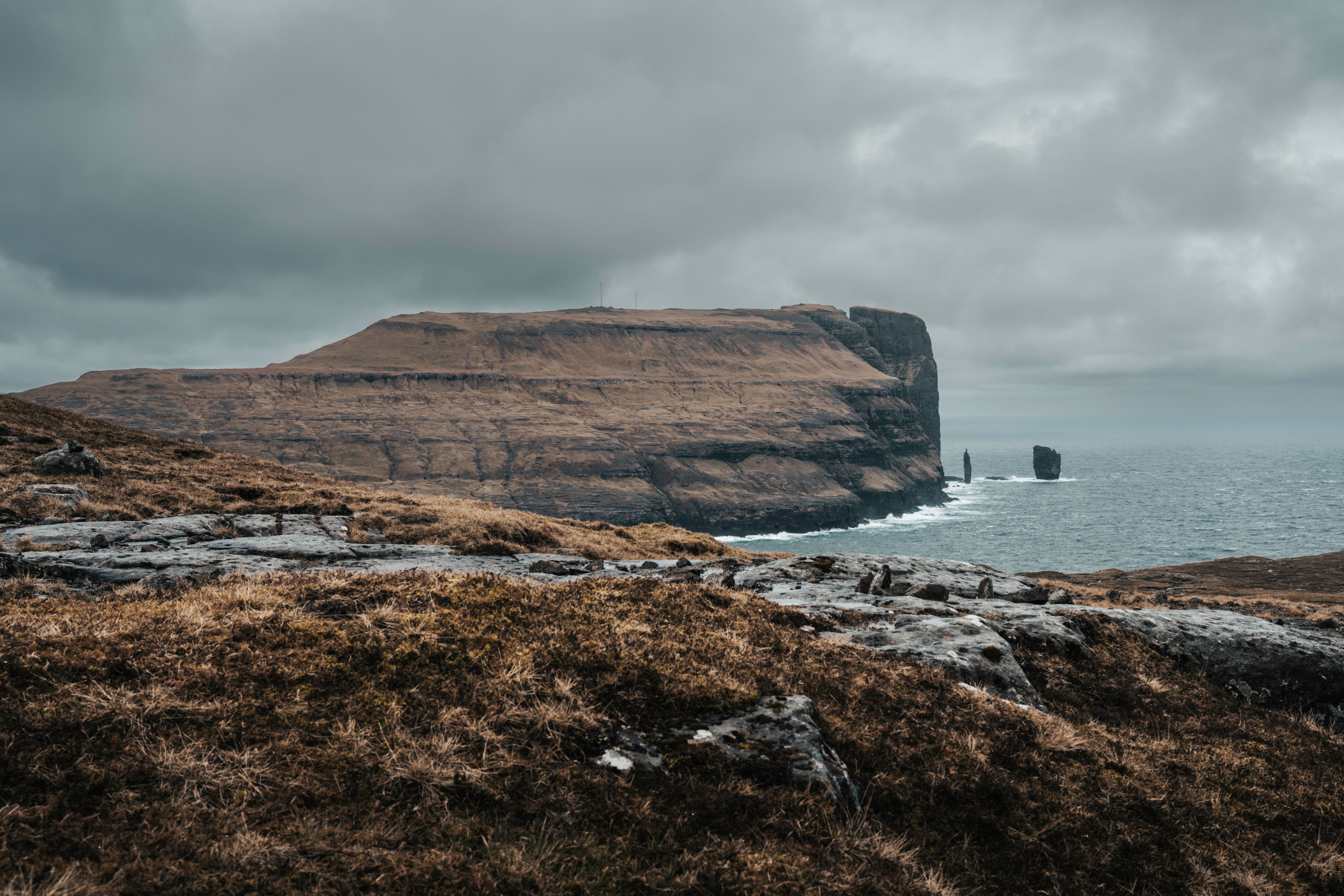 Majestic coastal cliffs under a dramatic cloudy sky, creating a stunning seascape view.