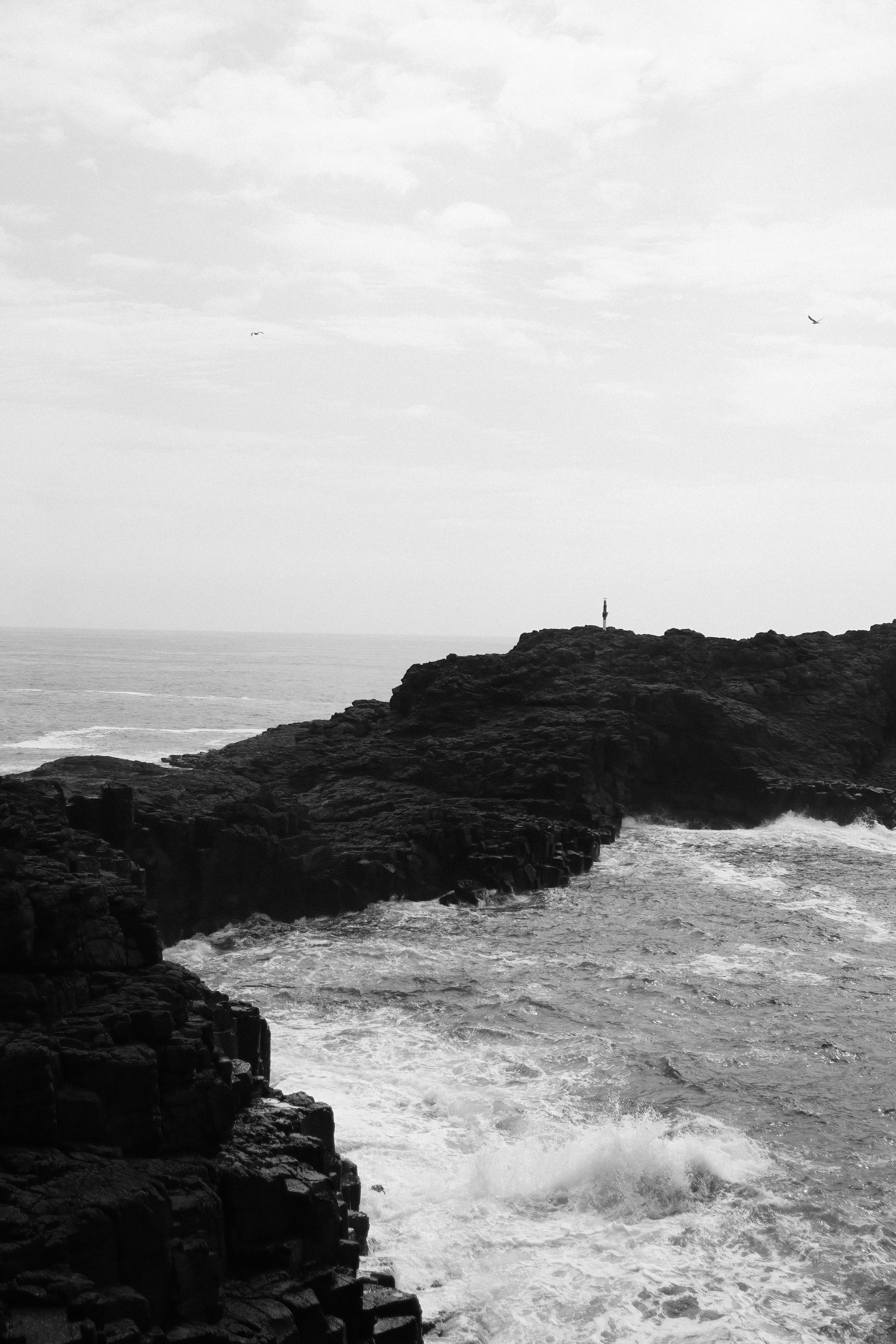 Waves crash against cliffs in a breathtaking black and white seascape.