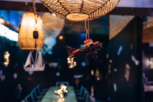 Cozy cafe interior featuring a hanging model airplane and warm decorative lighting, creating an inviting atmosphere.