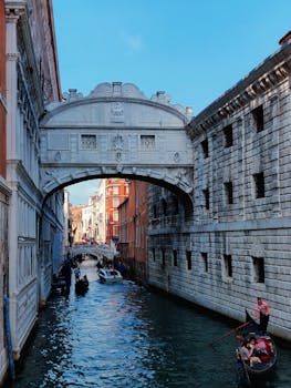 在风景优美的威尼斯水道中，贡多拉从历史悠久的萨科桥下经过