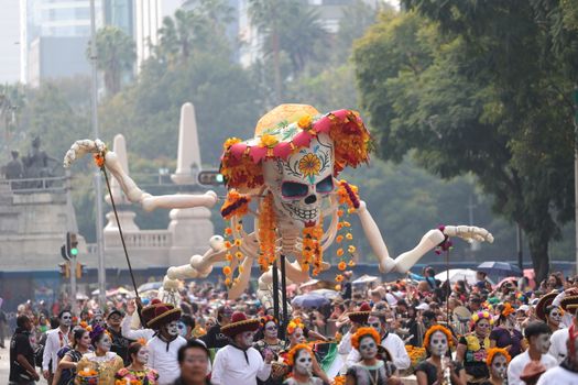 Colorful Day of the Dead parade with vibrant costumes and a giant skeleton in Mexico City.