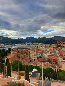 Dramatic sky over Cartagena cityscape with mountains and ancient ruins.