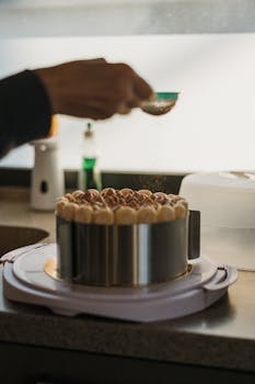 Artistic shot capturing the delicate process of assembling a layered mascarpone cake in a cozy kitchen.
