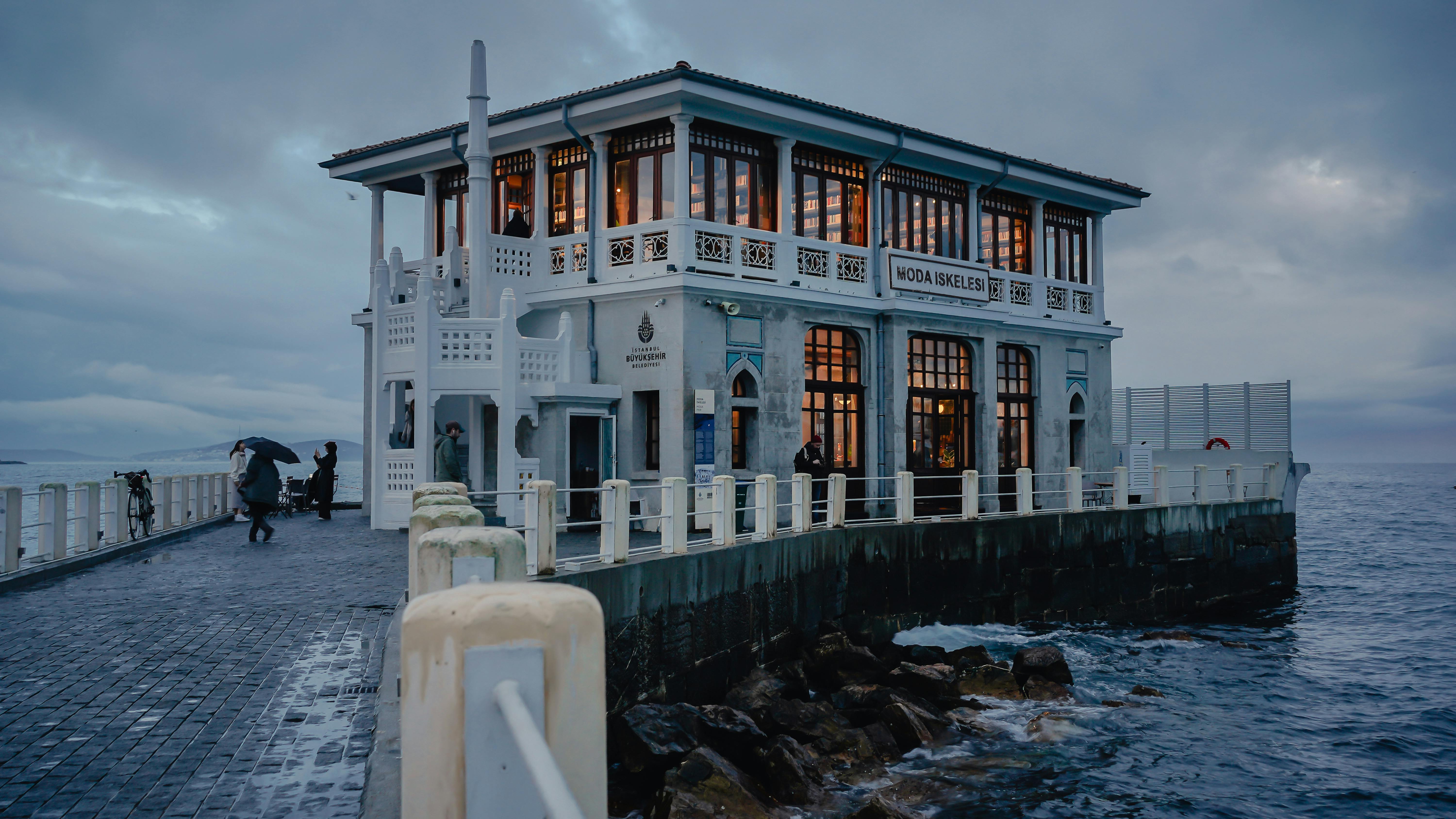 Gratis Una vista panorámica del muelle de Moda con luces cálidas brillando, con el telón de fondo de la costa crepuscular en Estambul. Foto de stock