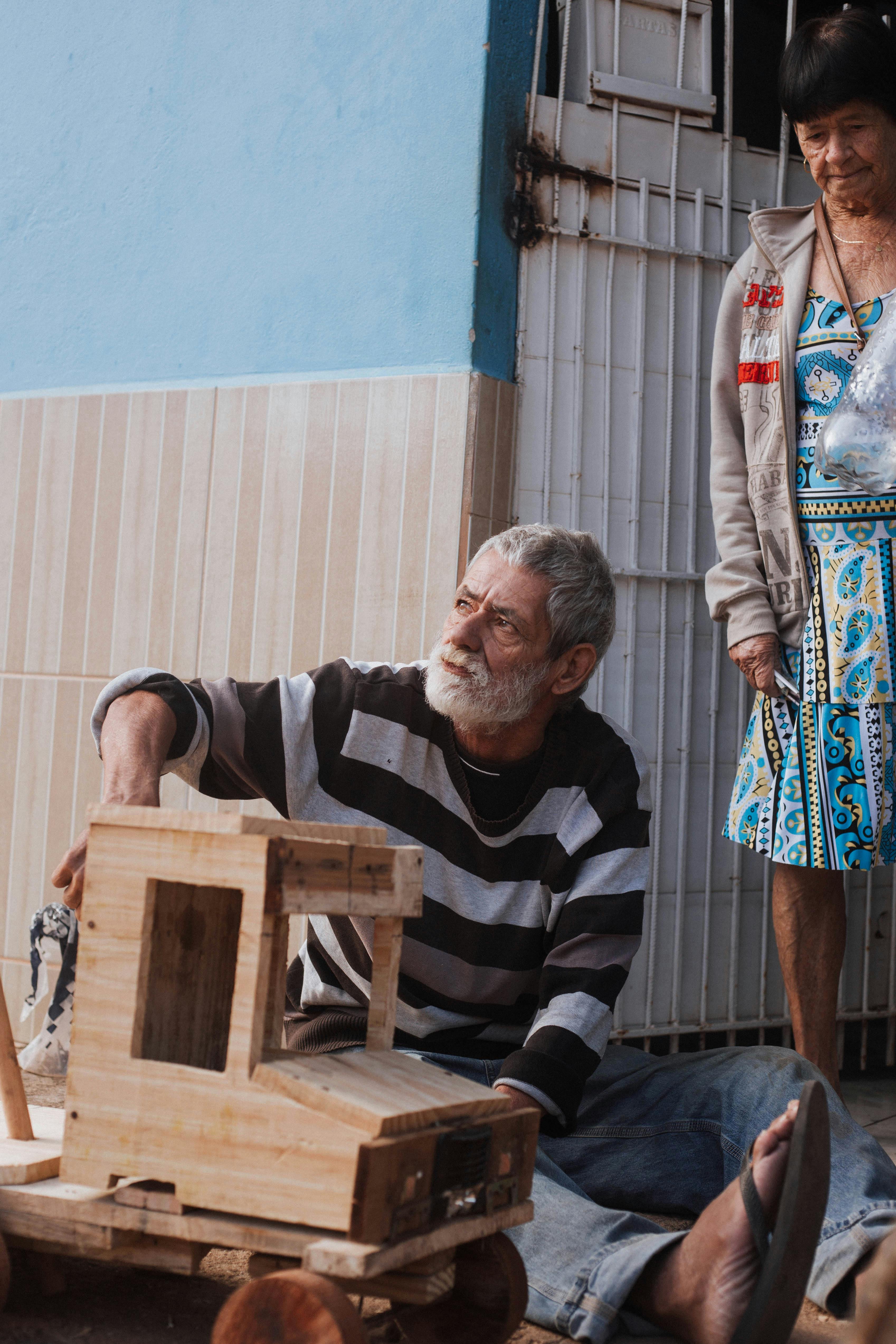Elderly man crafting a wooden toy vehicle, capturing artisanal craftsmanship in Tarumirim, Brazil.