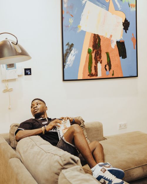 Free Man lounging on a couch reading a book, surrounded by modern art and soft lighting. Stock Photo