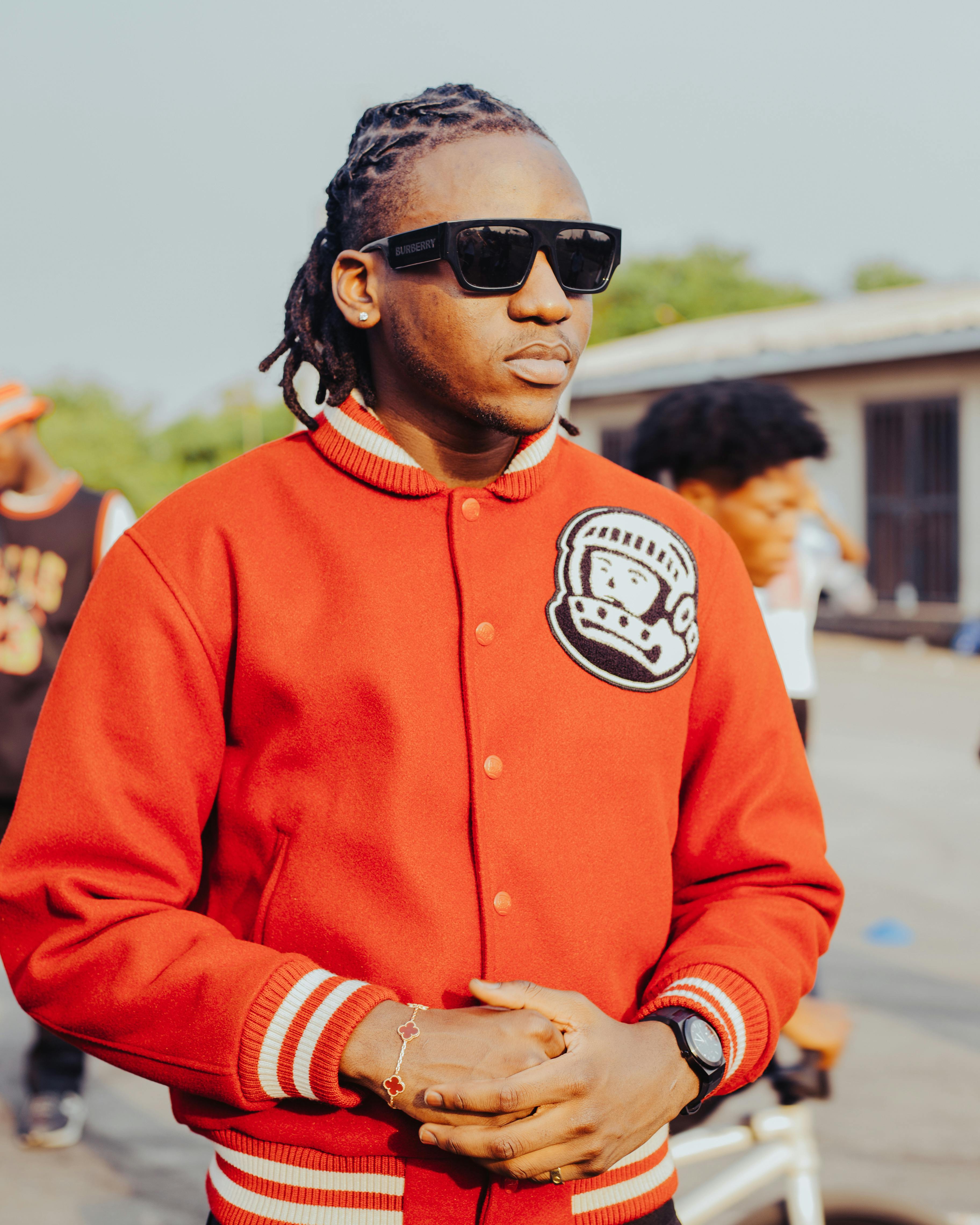Stylish man wearing sunglasses and a red jacket outdoors on a sunny day.