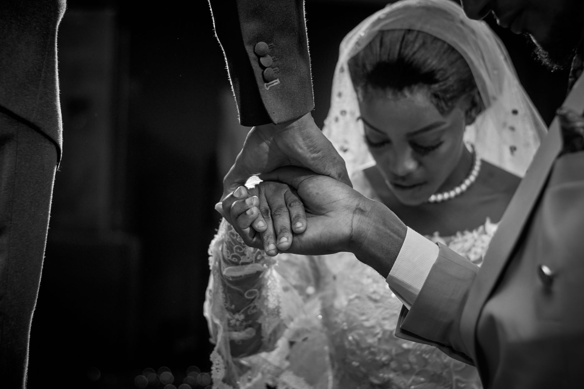 Capturing a heartfelt moment at an African wedding in Minna, Nigeria. A black and white photograph of a bride and groom holding hands in prayer.