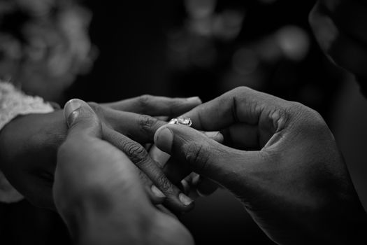 Romantic moment of placing an engagement ring in black and white photography. Intimate and elegant.