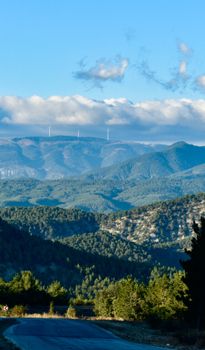 Breathtaking view of mountains and wind turbines under a clear blue sky.
