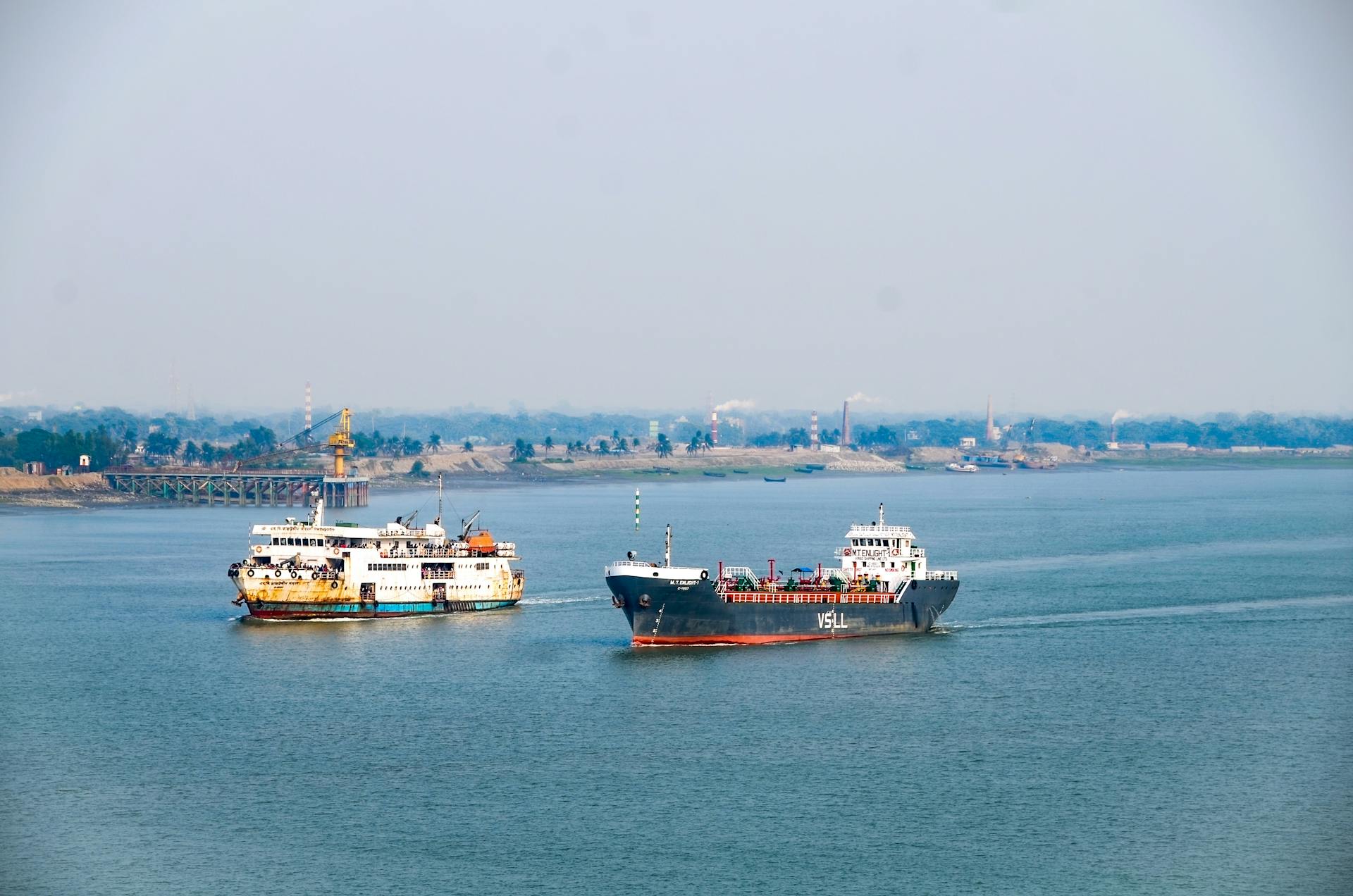 Two cargo ships crossing a wide river on a clear day, showcasing marine transport.