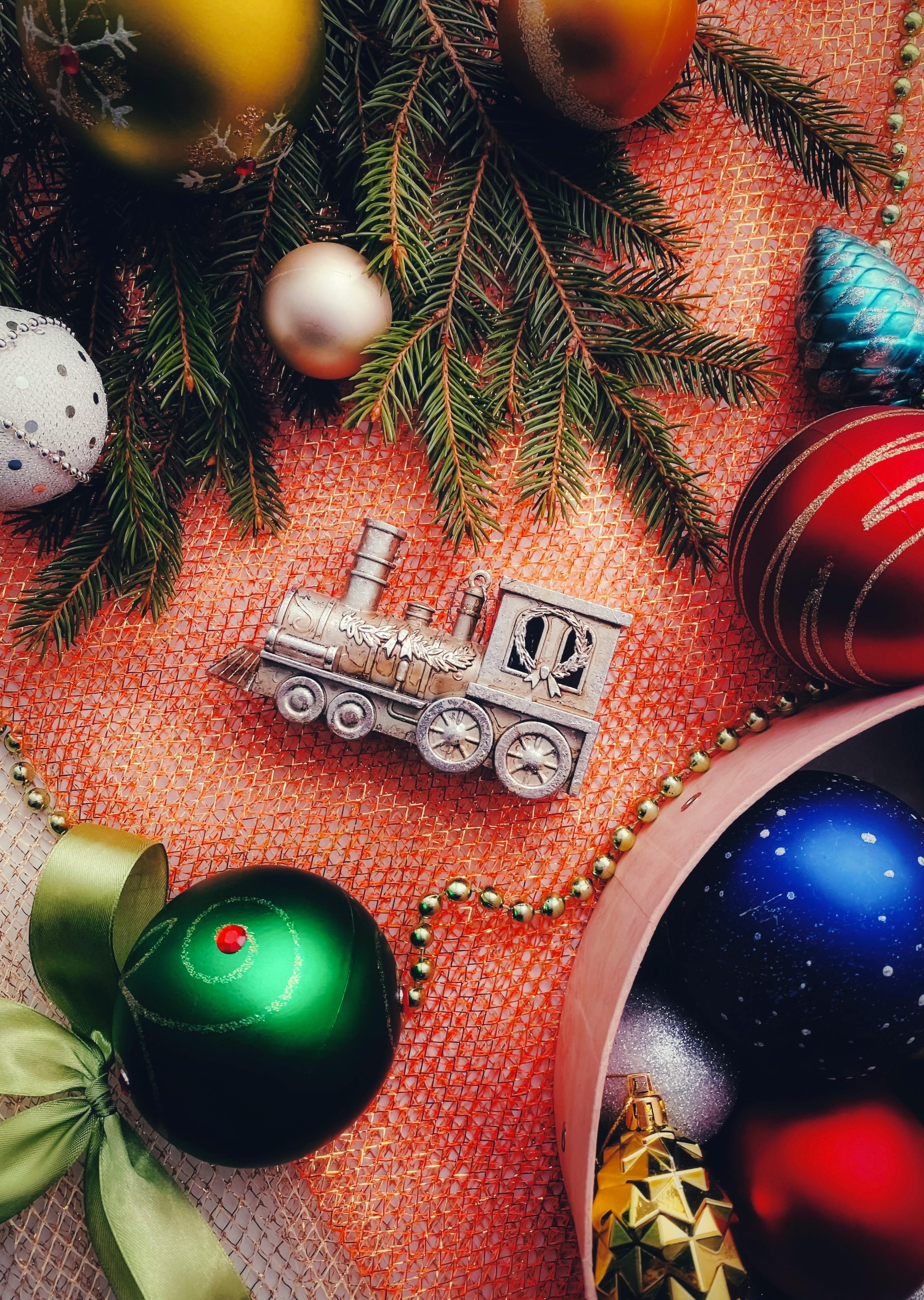 A festive arrangement of Christmas ornaments including a toy train and pine branches.