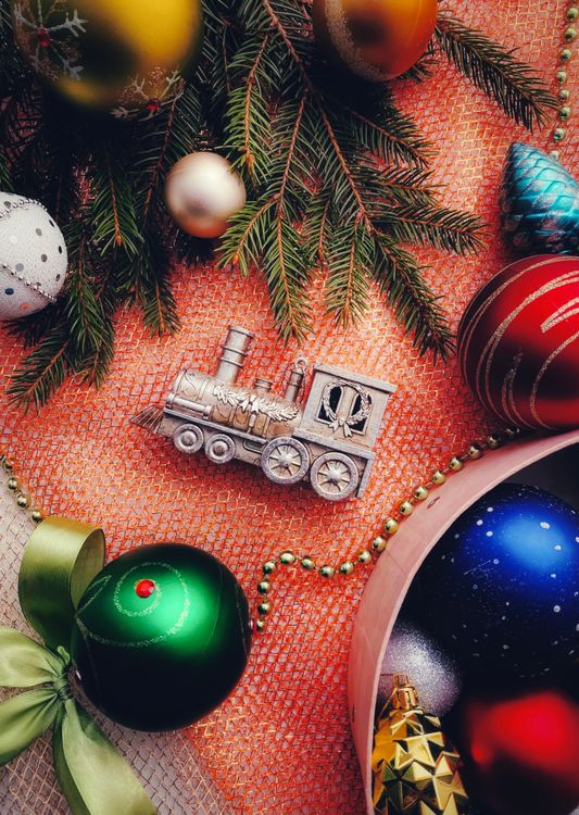 Gratis Un arreglo festivo de adornos navideños que incluye un tren de juguete y ramas de pino. Foto de stock