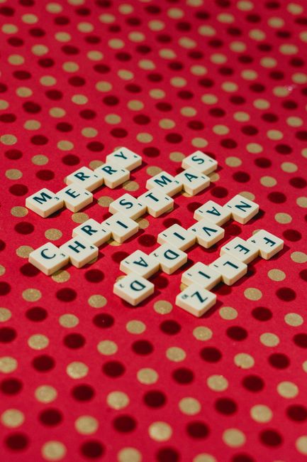 Scrabble tiles spelling 'Merry Christmas' on a festive red polka dot background.