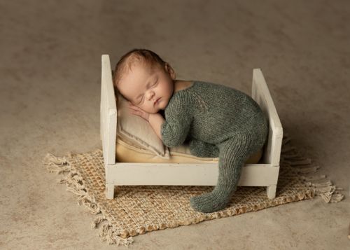 Free Cute baby sleeping on small rustic bed with knitted outfit. Perfect for nursery decor. Stock Photo