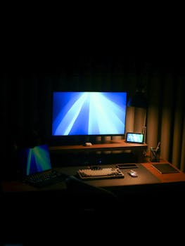 A minimalist home office desk with computers, perfect for productivity. Warm lighting creates a cozy atmosphere.