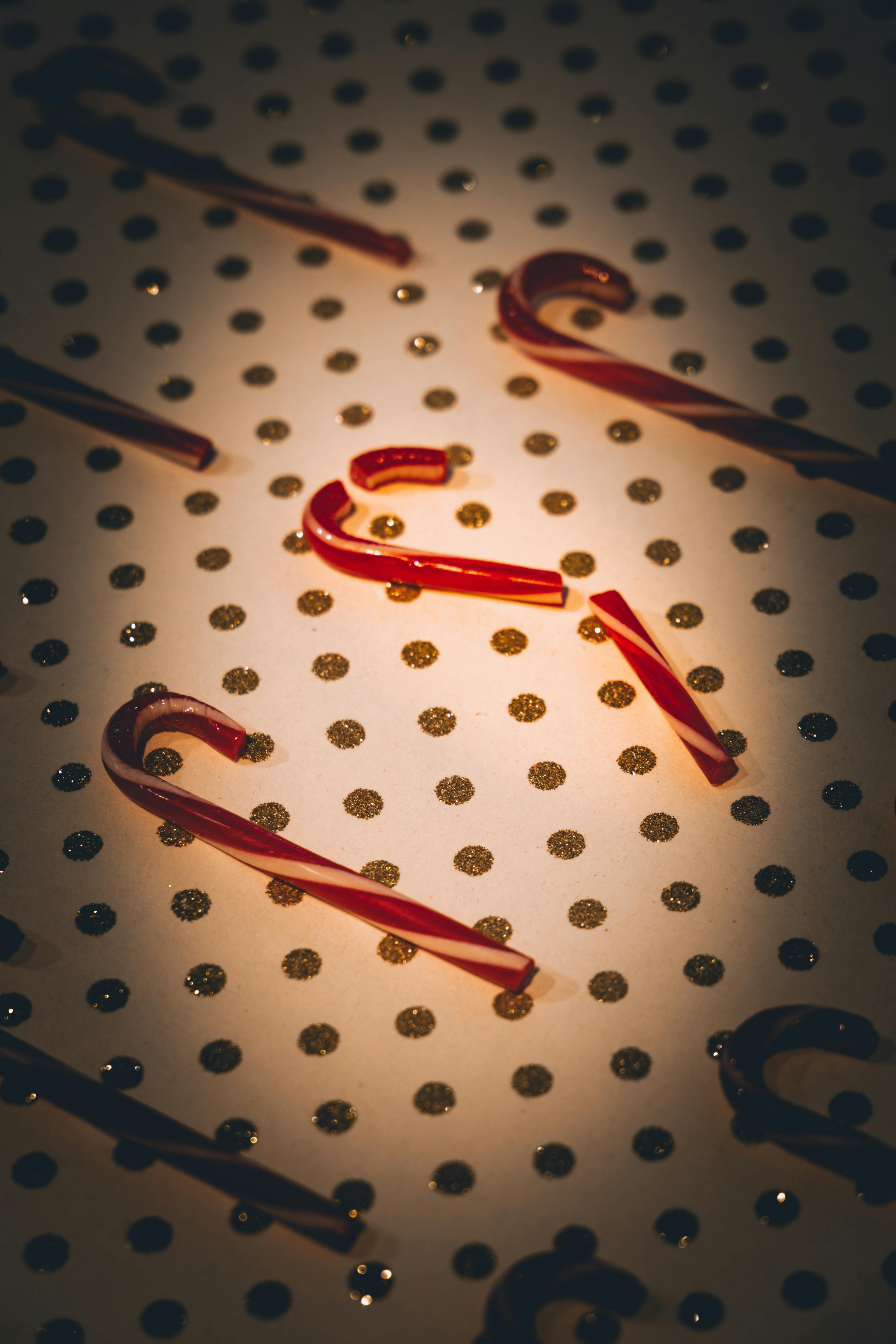Free Red candy canes scattered on glittery background. Perfect for Christmas decor. Stock Photo
