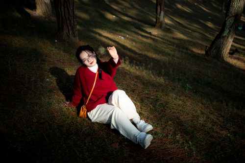 Free A woman in a red sweater enjoys sunlight in a forest in Hà Giang, Vietnam. Stock Photo