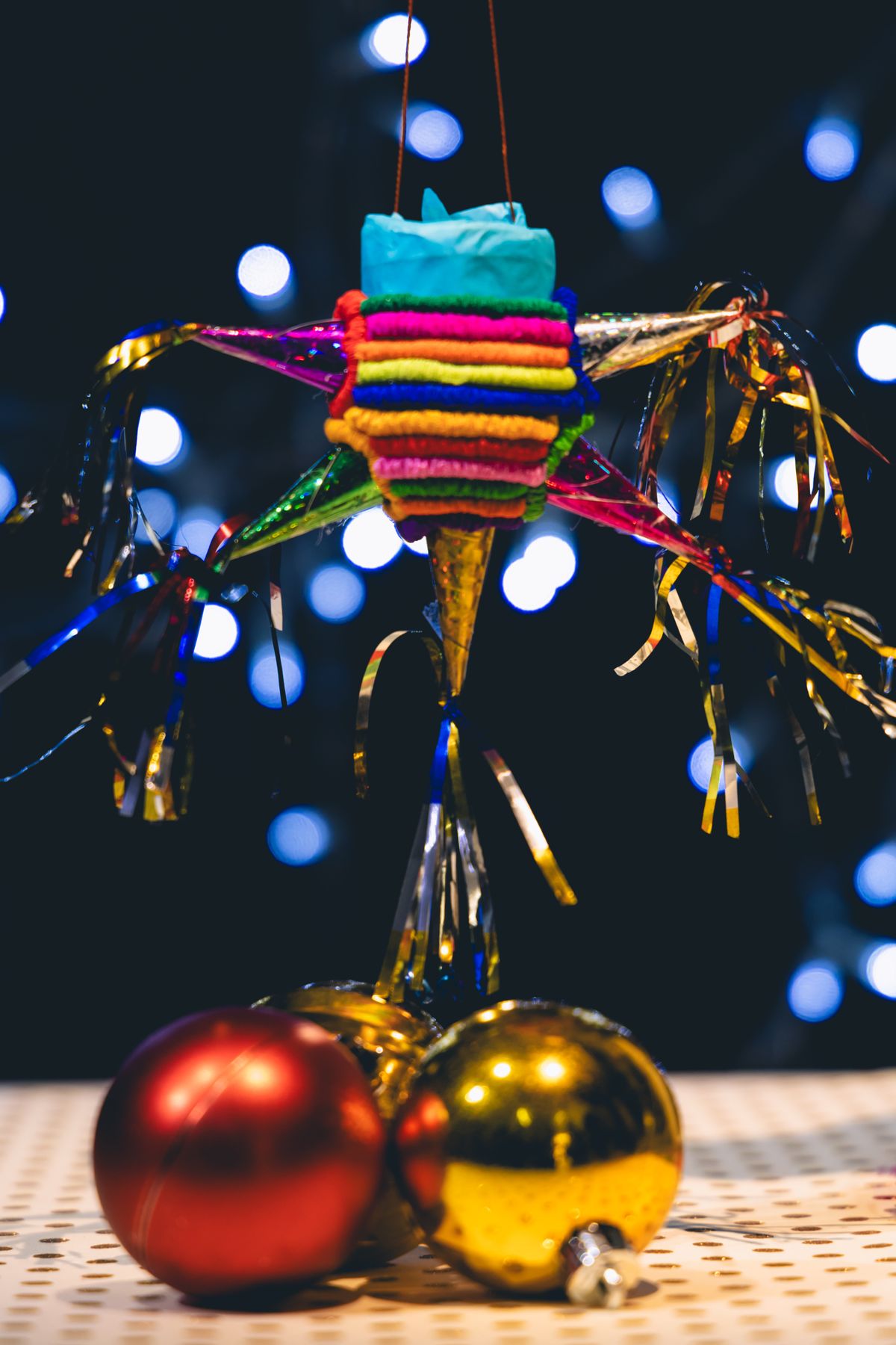 Festive colorful piñata with Christmas ornaments against a sparkling light background.