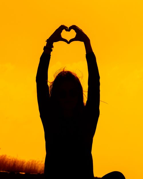 Free A beautiful silhouette of a person creating a heart shape with hands against a vibrant sunset in Kayseri, Türkiye. Stock Photo