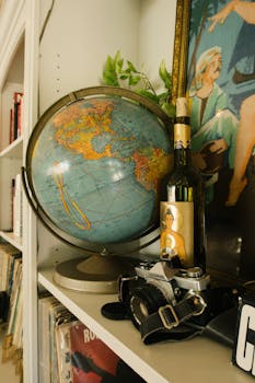 复古地球仪、酒瓶和相机在架子上营造出艺术学习的氛围
