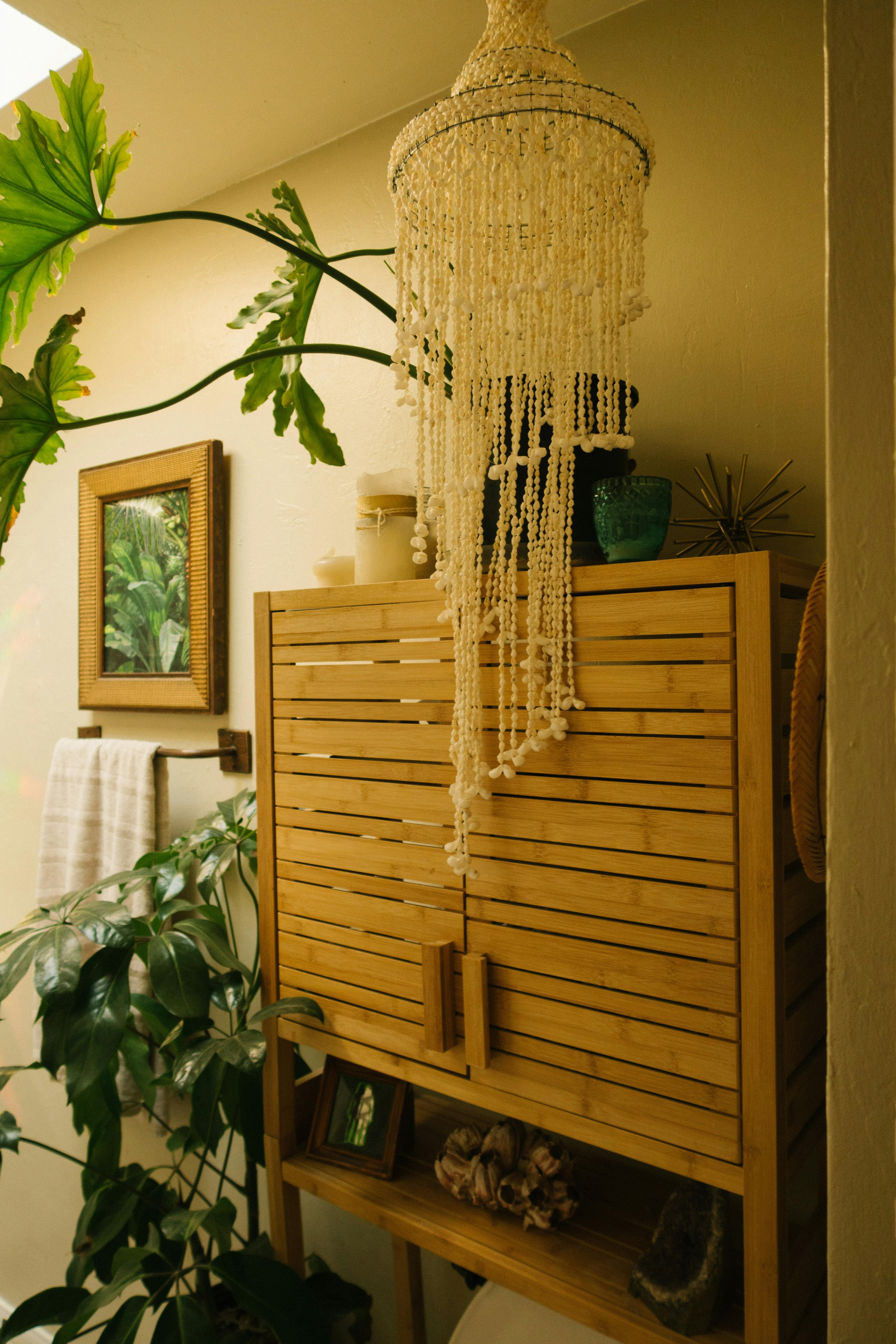 Bamboo cabinet with indoor plants and bohemian chandelier in cozy home setting.