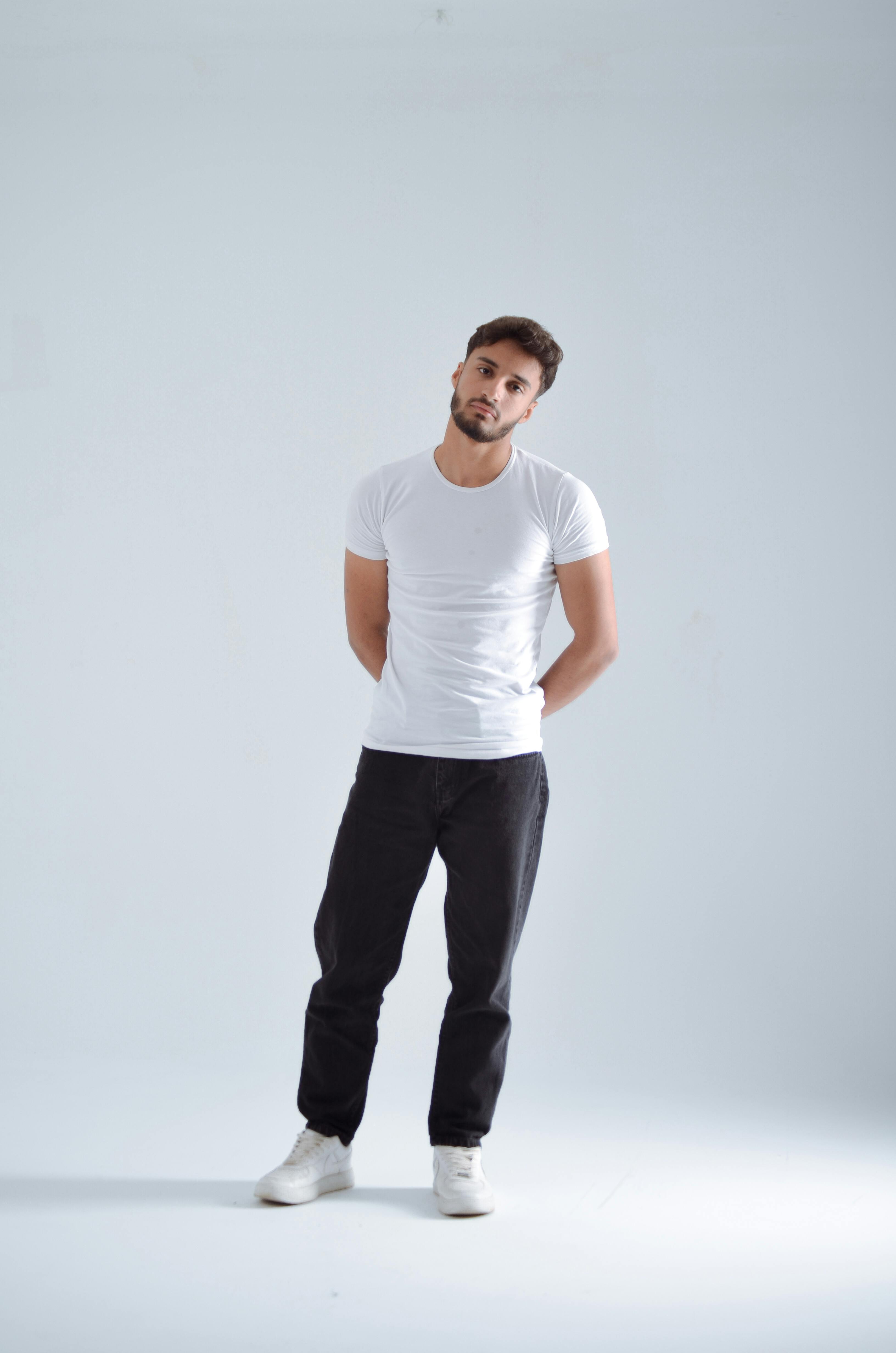 bezplatná Mladý muž v neformálním oblečení pózuje uvnitř s neutrálním pozadím. Základová fotografie