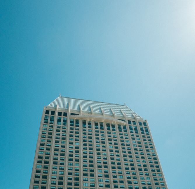 Low angle view of a modern skyscraper under a bright blue sky.