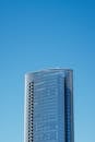 一座时尚的现代摩天大楼在万里无云的蓝天下耸立，展现了当代建筑的魅力