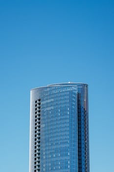 一座时尚的现代摩天大楼在万里无云的蓝天下耸立，展现了当代建筑的魅力