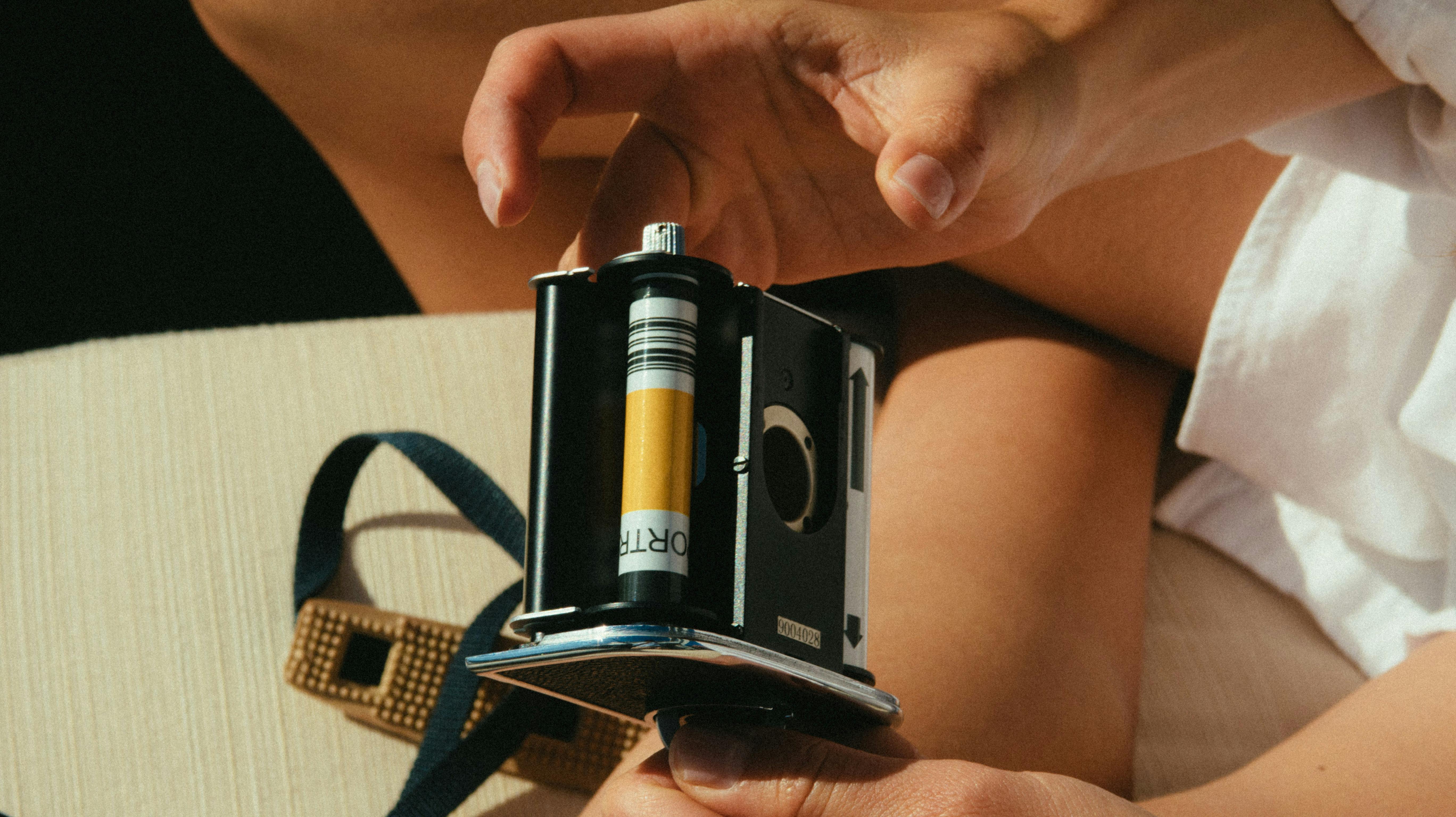 特写镜头中，一双手在室内操作着带胶片的复古相机