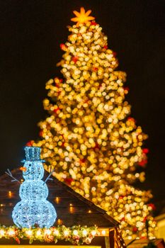 A glowing snowman and beautifully lit Christmas tree create a magical holiday atmosphere.