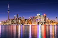 在清澈的夜空下，加拿大国家电视塔照亮了多伦多的天际线，映照着平静的水面